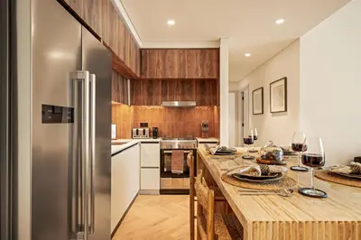 a kitchen with a refrigerator and a table with wine glasses at Seraya Residences at Marina Vista, Emaar Beachfront in Dubai