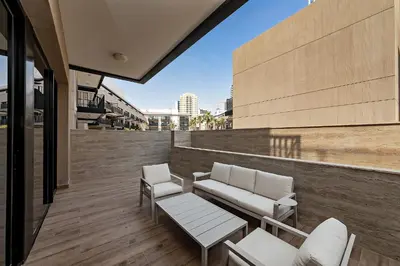 a balcony with white chairs and a bench on a building at Oakley Square 1BR Apartment with maid's room in Dubai