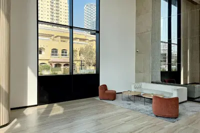a living room with a couch and chairs and large windows at Oakley Square 1BR Apartment with maid's room in Dubai
