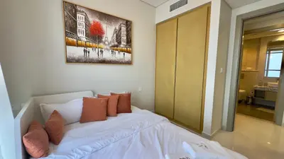 a bedroom with a white bed and a painting on the wall at Guest Favorite - 2BR Apartment 57th Floor Close to Downtown in Dubai