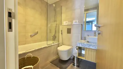 a bathroom with a toilet and a tub and a sink at Guest Favorite - 2BR Apartment 57th Floor Close to Downtown in Dubai