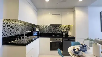a kitchen with white cabinets and black appliances at Guest Favorite - 2BR Apartment 57th Floor Close to Downtown in Dubai