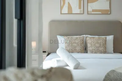 a white bed with pillows and towels on it at Steps from Dubai Hills Mall, Surrounded by Top-Tier Amenities, and close to Dubai Hills Park and Golf Club, Socio Tower 1, Dubai Hills by Deluxe Holiday Homes in Dubai