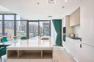 a kitchen with white cabinets and a large window at Premium 2BR with Pool, Gym & Lifestyle Amenities in Dubai