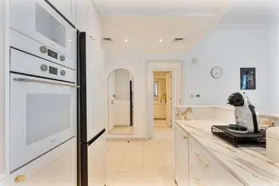 a kitchen with white cabinets and a black refrigerator at Upmarket - 1BR - Canal View - 9 MIN Dubai Mall in Dubai