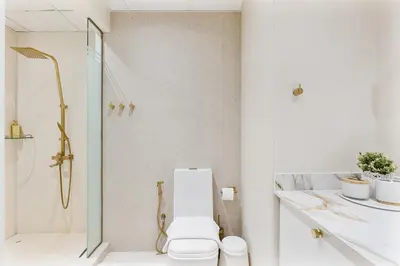 a white bathroom with a toilet and a shower at Upmarket - 1BR - Canal View - 9 MIN Dubai Mall in Dubai