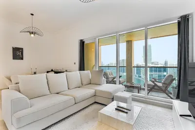 a living room with a white couch and large windows at Upmarket - 1BR - Canal View - 9 MIN Dubai Mall in Dubai
