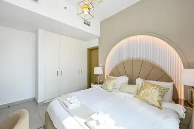 a bedroom with a large white bed with a wooden headboard at Golden Stays - Luxury 2BR I Burj Views & Direct Dubai Mall Access in Dubai