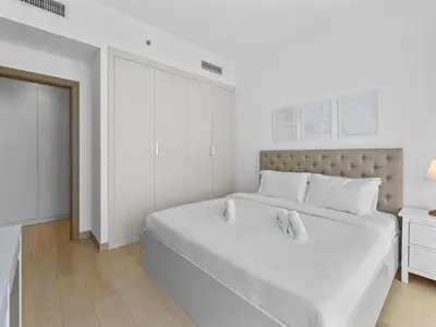 a white bedroom with a large bed and a doorway at Bright 1 Bedroom Apartment with JVC open view in Dubai