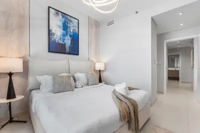 a white bedroom with a large white bed and two lamps at Guest Favorite - Luxury 2BR with Full Burj Khalifa View Downtown in Dubai