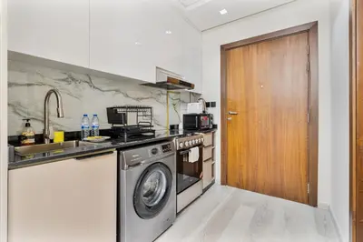 a kitchen with a washing machine and a wooden door at Sunny Studio with Pool, Near Silicon Central Mall in Dubai