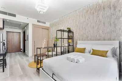 a bedroom with a large white bed with two towels at Sunny Studio with Pool, Near Silicon Central Mall in Dubai
