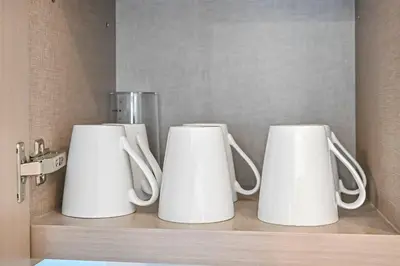 three white coffee mugs sitting on a shelf at Stylish 2BR Downtown Dubai in Dubai