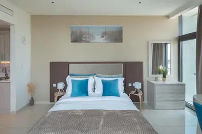 a bedroom with a large bed with blue pillows at Beachfront Studio at West Beach in Dubai