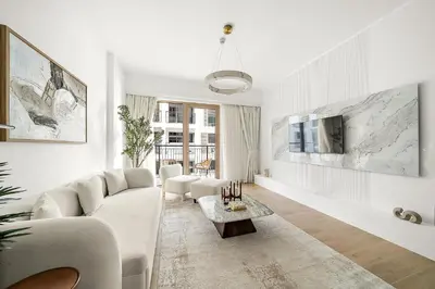 a white living room with a couch and a tv at Luxury La Mer 1BR Balcony Sea Views Near City Walk and Mall in Dubai