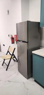 a stainless steel refrigerator in a kitchen with a chair at Opalz by danube science park in Dubai