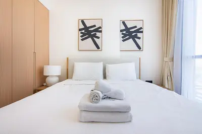 a bedroom with a white bed with towels on it at Brand New 1 Bedroom in AURA by Grovy, JVC in Dubai