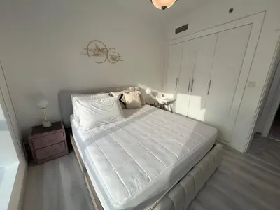 a bedroom with a large white bed with a night stand at Italian-Style 2BR - Near Beach, Metro and Mall in Dubai