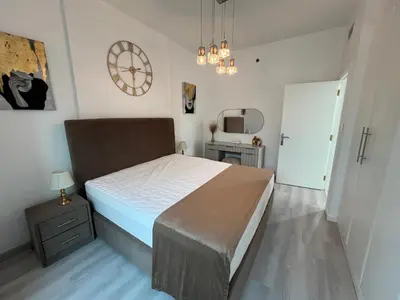 a bedroom with a bed and a clock on the wall at Italian-Style 2BR - Near Beach, Metro and Mall in Dubai