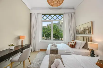a bedroom with two beds and a desk and a window at Elegant Private Room at The Palm with Beach & Pool Access in Dubai