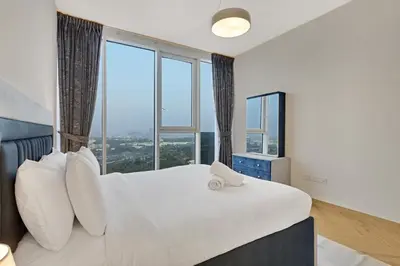 a bedroom with a large white bed with large windows at 1 Residences High-Floor Apt with City View, Al Kifaf in Dubai