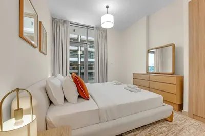 a white bedroom with a large bed and a window at Canal View, Partial Burj Khalifa View, Brand New in Dubai