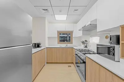 a large kitchen with white counters and wooden cabinets at Canal View, Partial Burj Khalifa View, Brand New in Dubai