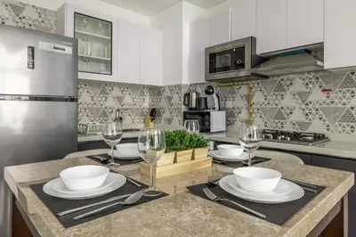 a kitchen with a table with plates and wine glasses at stylish 1BR Pearlz Pool & Gym Near Metro in Dubai