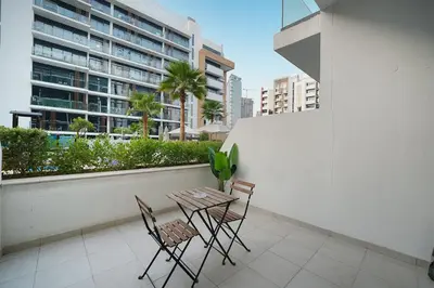 a table and chairs on a balcony with a building at EasyGo- Spacious, Low Floor and Pool view STU in Dubai
