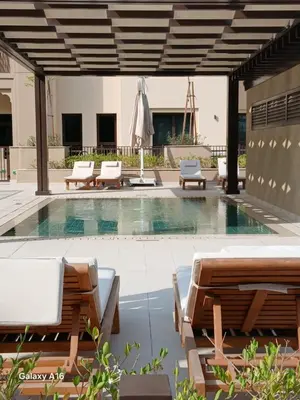 a swimming pool with lounge chairs and an umbrella at Madinat Jumeirah Living 1 Bedroom Holiday Rental in Jadeel 3 - DVH Holiday Homes in Dubai