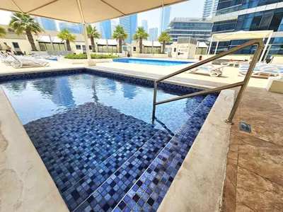 a swimming pool with a blue tile floor and an umbrella at Opposite JBR Beach - Modern Studio in Dubai