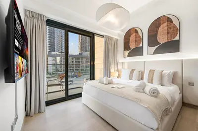 a bedroom with a large white bed and a large window at Stylish 1BR with Netflix Pool & Gym Access in Dubai