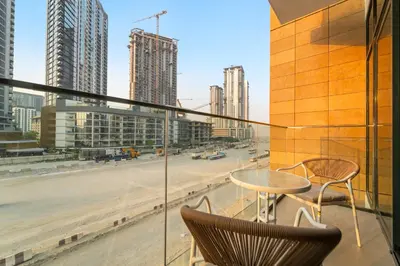 a balcony with a table and chairs and a view of a city at Stylish 1BR with Netflix Pool & Gym Access in Dubai