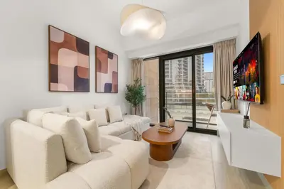 a living room with a white couch and a tv at Stylish 1BR with Netflix Pool & Gym Access in Dubai