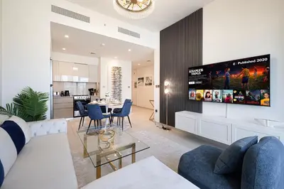 a living room with a couch and a tv on a wall at Burj Royale Luxury 2BR Burj Khalifa & Fountain View 5 Min Walk Dubai Mall, 500MBPS Wifi in Dubai