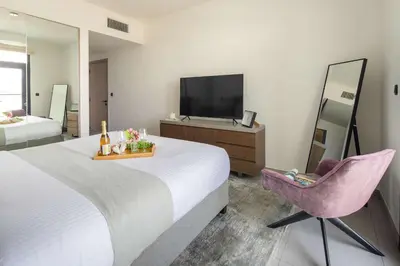 a bedroom with a bed and a chair and a television at Frank Porter - Hyati Avenue in Dubai
