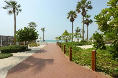 a walkway leading to the beach with palm trees at High-end Beachfront 4BR Duplex with Patio Sea and Burj View in Dubai