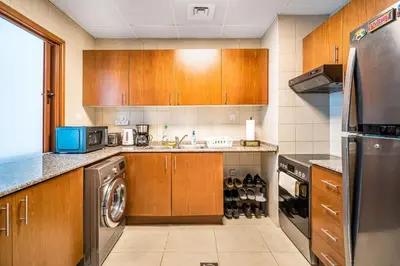 a kitchen with wooden cabinets and a washer and dryer at MAG218 Cozy 1BHK Near Marina Walk in Dubai