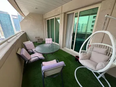 a balcony with chairs and a glass table and a swing at Cozy 1BR apartment in Marina in Dubai