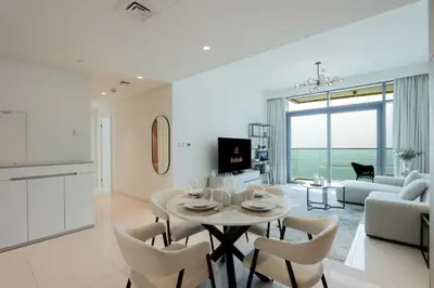 a kitchen and living room with a table and chairs at Sea View 2B Beachfront Luxury Emaar Beachfront in Dubai
