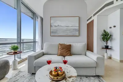a living room with a couch and two glasses of wine at DAYF-SKGMAR Upgraded Huge High-Floor Studio with Dubai Frame View in Dubai