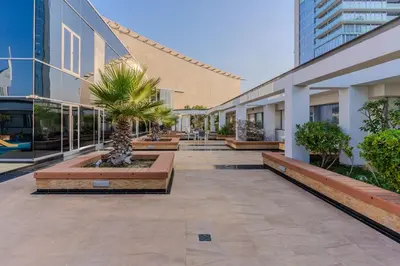 a courtyard with benches and palm trees in a building at DAYF-SKGMAR Upgraded Huge High-Floor Studio with Dubai Frame View in Dubai