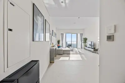 a white hallway with a living room with a couch at Luxury 2BR at Signature Grande - Next to Dubai Mall & Burj Khalifa in Dubai