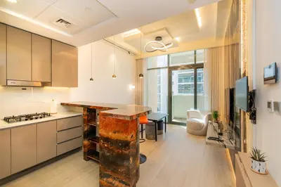 an apartment kitchen with a counter and a living room at Elite Escape - 1 BHK Getaway in Azizi Riviera 18 in Dubai