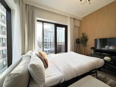 a bedroom with a large bed and a large window at Chic & Sunny 1BR Escape At Grove Creek Beach Access in Dubai
