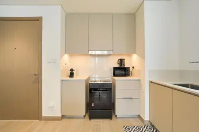 a small kitchen with a stove and a microwave at Chic & Sunny 1BR Escape At Grove Creek Beach Access in Dubai