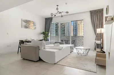 a white living room with a white couch and a table at FIRST CLASS 1BR Stylish Beachfront Escape in Dubai