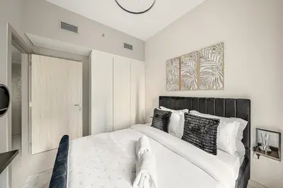 a bedroom with a white bed with a black headboard at FIRST CLASS 1BR Modern Serenity in Dubai