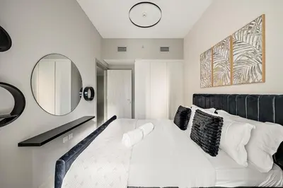a bedroom with a bed with a clock on the wall at FIRST CLASS 1BR Modern Serenity in Dubai