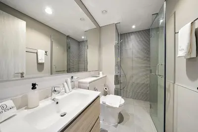 a bathroom with a sink and a toilet and a shower at FIRST CLASS 1BR Modern Serenity in Dubai